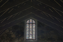 a stained glass window and ceiling beams in a church 