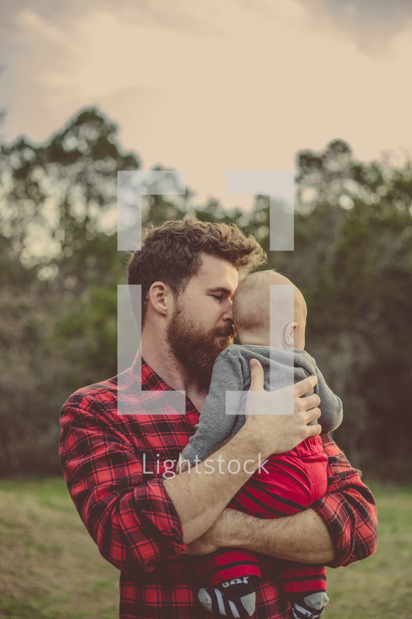 Father holding his infant son outside.