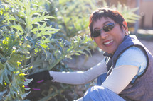 Smiling woman wearing sunglasses while gardening.