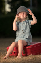 toddler girl sitting on a suitcase 