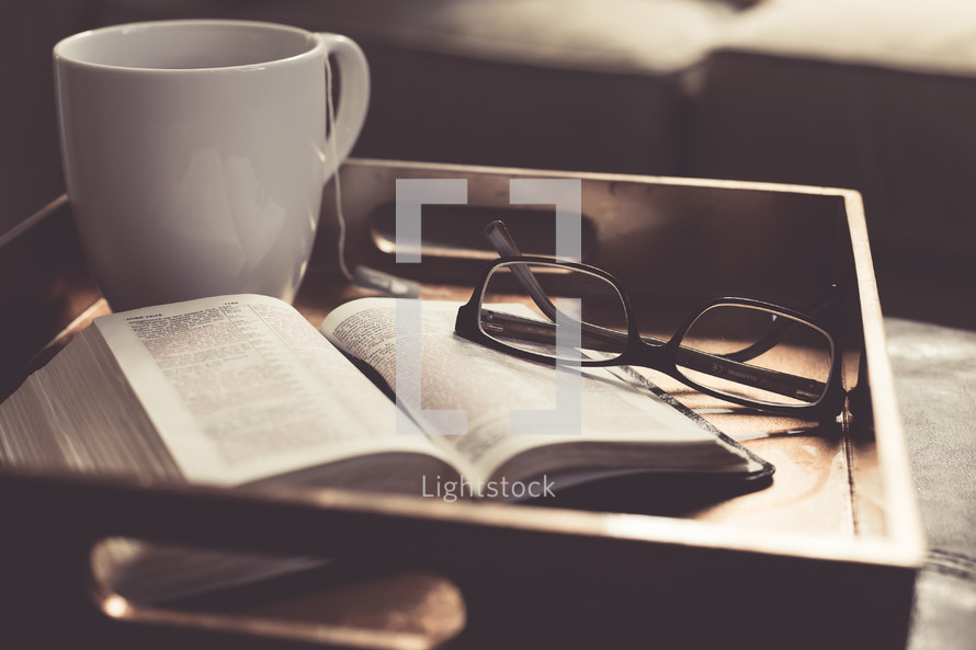 tea cup, open Bible, and reading glasses on a tray 