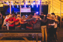 group of people hugging at a concert 
