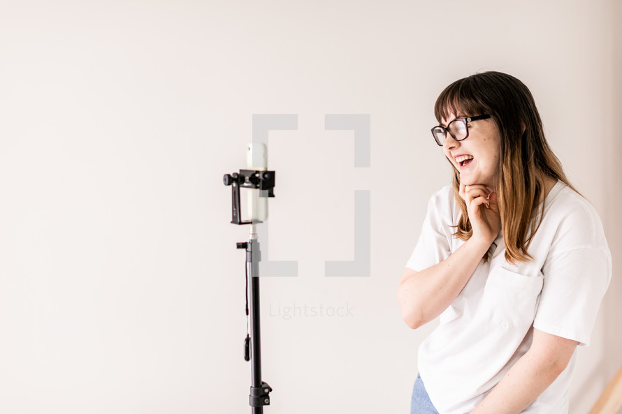 young woman talking into a phone on a tripod 
