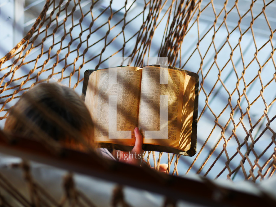 a woman reading a Bible in a hammock 
