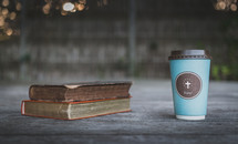 coffee cup with cross and books on wood ledge 