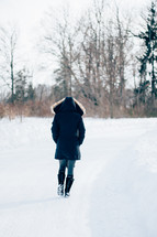 woman in a winter coat walking in snow 
