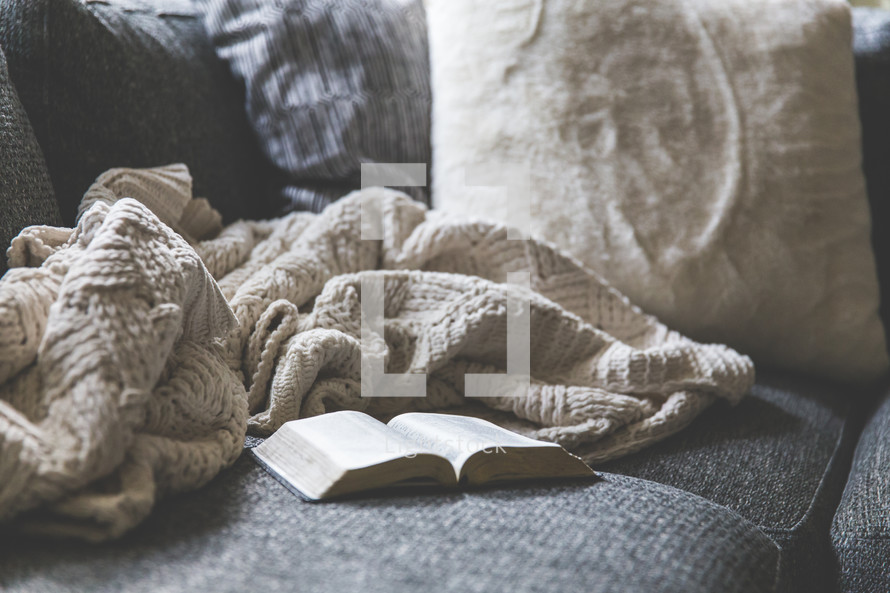 blanket and open Bible on a couch 