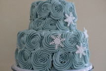 Blue buttercream frosting and sugar snowflakes on a cake