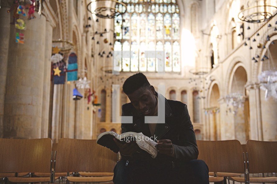 a man reading a Bible in an empty church 