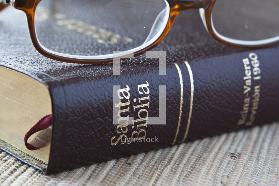 Reading glasses resting on Spanish Bible.