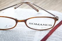Reading glasses reasting on open page of Spanish Bible.