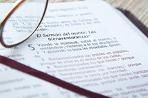 Reading glasses resgin on open page of Spanish Bible.