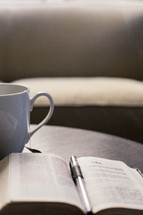 Coffee cup and a pen on the pages of a Bible 
