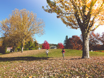 children running through fall leaves 