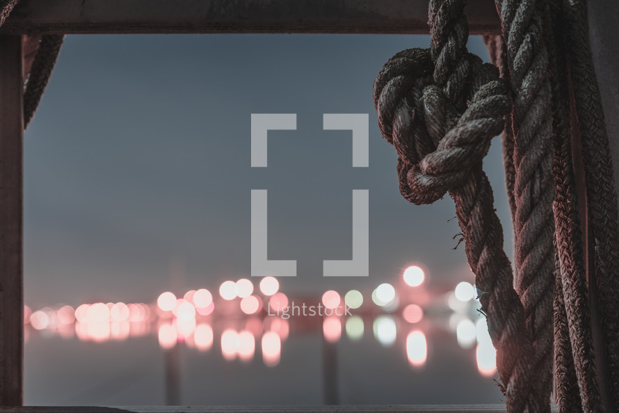 rope in a window and view of lights over docks 