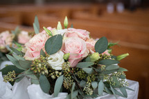 Wedding bouquet of flowers in front of wooden pews