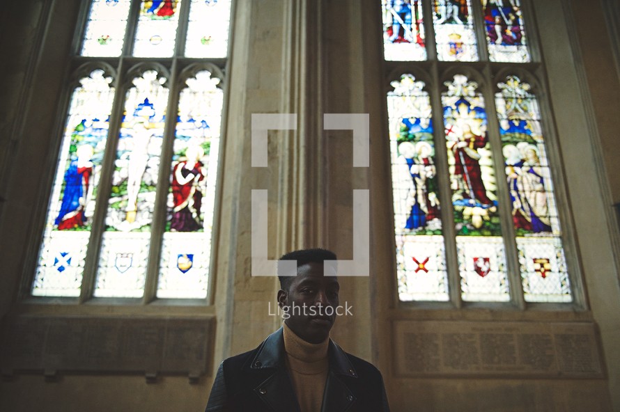 man standing in a church in front of stained glass windows 