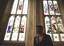 man standing in a church in front of stained glass windows 