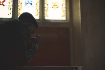 a man kneeling in prayer in a church 