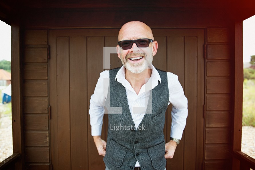 a bald man in sunglasses and a vest 
