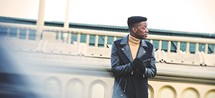 African American man in a leather jacket standing in front of a building outdoors 
