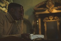 a man in prayer holding a Bible in a church
