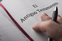 Hand holding pen on Spanish Bible.
