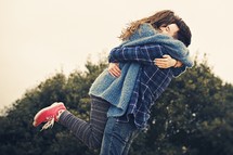 a happy young couple hugging outdoors 