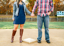 couple holding hands on a baseball field 