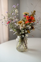 flowers in a jar on white table 