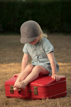 a toddler sitting on a suitcase 