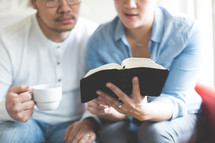 A man and woman reading a Bible together 