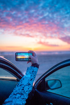 taking a picture of sunset at a beach 