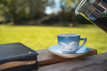 tea cup and Bible on a bench 