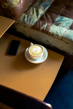 a latte on an end table next to a couch 