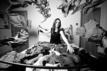 woman sitting on a bed covered in clothes and shoes