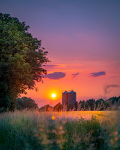 silos under an orange and purple sky at sunset 