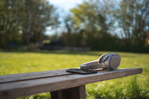 headphones and cellphone on a bench 