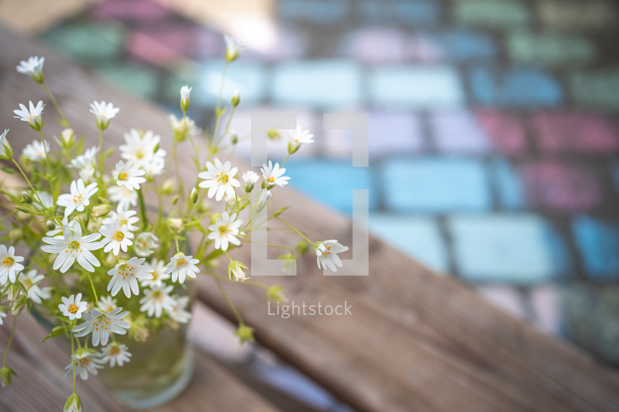 flowers in a vase on a bench 
