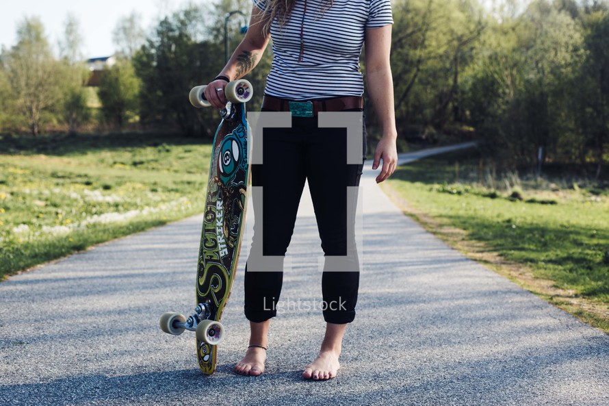 a teen girl standing holding a skateboard 