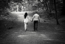 man and woman holding hands walking country lane