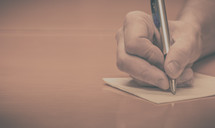 a man writing a letter with a pen 