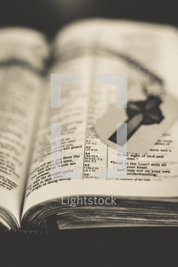 A dog tag with a cross on the pages of a Bible. 