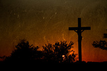 silhouette of a sculpture of the crucifixion of Christ at sunset