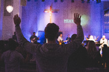 people in a congregation standing with raised hands 