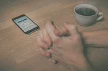 praying hands by a cellphone opened to an app for online giving 