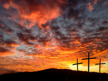 silhouette of three crosses against a fiery sky 