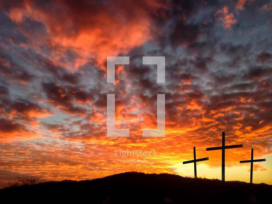 silhouette of three crosses against a fiery sky 