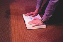 a man kneeling before an altar with a Bible 