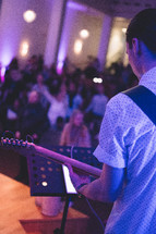 a man playing a guitar during a worship service 